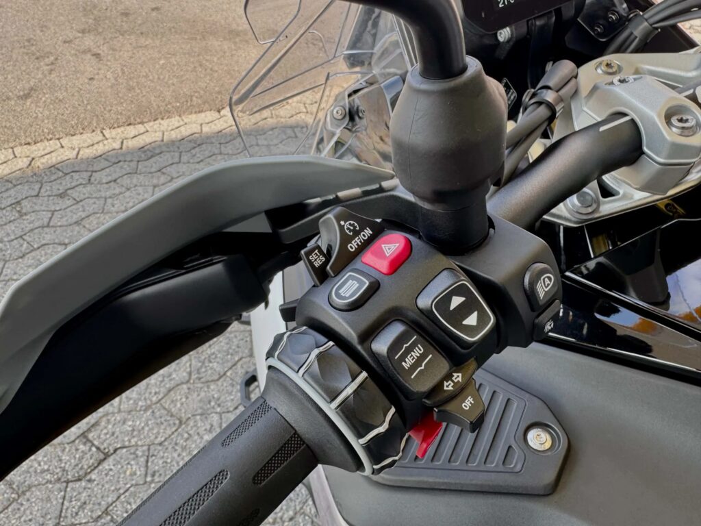 Nærbilde av venstre håndtak på BMW R 1300 GS Adventure med knapper for cruisekontroll, meny og varselblink, som illustrerer mangelen på kløtsjhendel på ASA-automatgirkassen