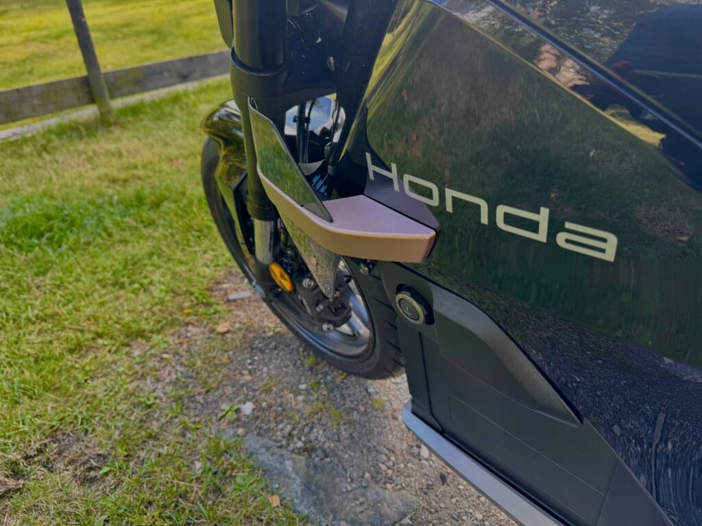 Nærbilde av Honda WN7 som viser den uvanlige plasseringen av av- og påknappen på siden av motorsykkelen, ved siden av forhjulet og Honda-logoen