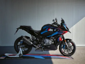 BMW M 1000 XR i svart med blå og røde M-detaljer, vist i profil på BMW Motorrad-matte. Beepi.no / Bikelifenorge.no