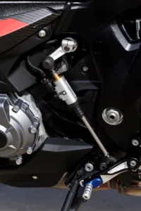 Nærbilde av quickshifter-mekanismen og girstangen på BMW M 1000 XR, med synlig motordeksel og fotstøtte. Beepi.no / Bikelifenorge.no